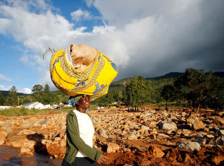 A survivor carries supplies on her head as she moves to higher ground at Ngangu suburb in Chimanimani, Zimbabwe, March 22, 2019. REUTERS/Philimon Bulawayo