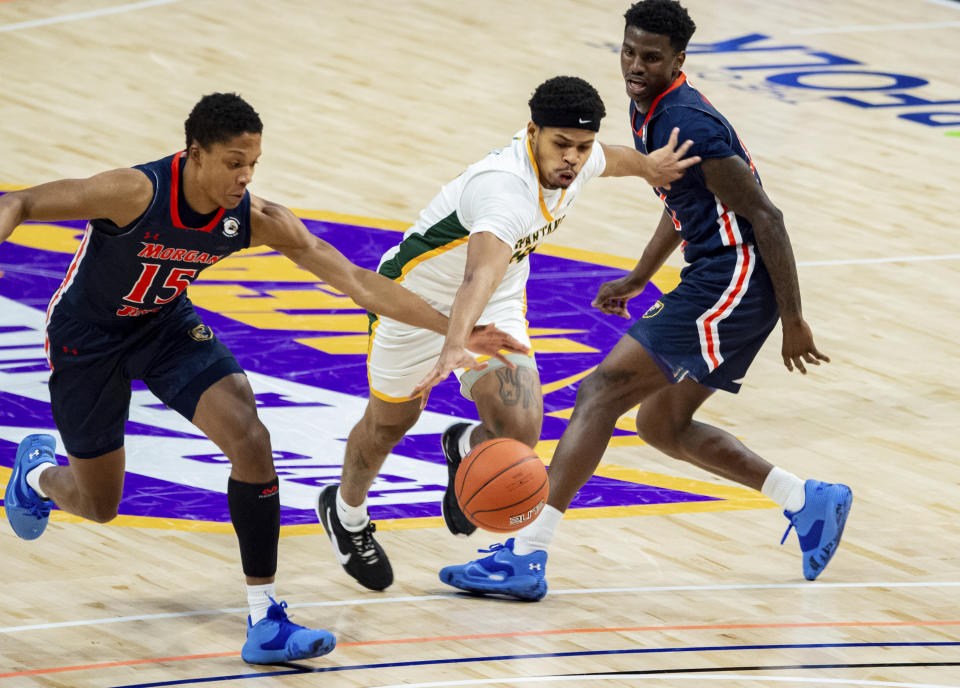 Norfolk State's Devante Carter, center, drives past Morgan State's Tahj-Malik Campbell, left, and Malik Miller, right, during the first half of of an NCAA college basketball game in the championship of the Mid-Eastern Athletic Conference tournament at the Scope Arena on Saturday, March 13, 2021, in Norfolk, Va. (AP Photo/Mike Caudill)