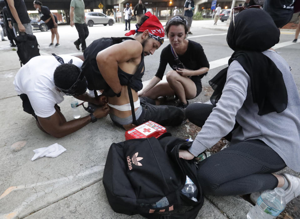 Demonstrators attend to a man hit by a rubber bullet during a demonstration next to the city of Miami Police Department, Saturday, May 30, 2020, downtown in Miami. Protests were held throughout the country over the death of George Floyd, a black man who died after being restrained by Minneapolis police officers on May 25. (AP Photo/Wilfredo Lee)