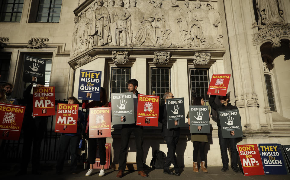 Protesters hold banners outside the Supreme Court in London, Tuesday Sept. 17, 2019. The Supreme Court is set to decide whether Prime Minister Boris Johnson broke the law when he suspended Parliament on Sept. 9, sending lawmakers home until Oct. 14 — just over two weeks before the U.K. is due to leave the European Union. (AP Photo/Matt Dunham)