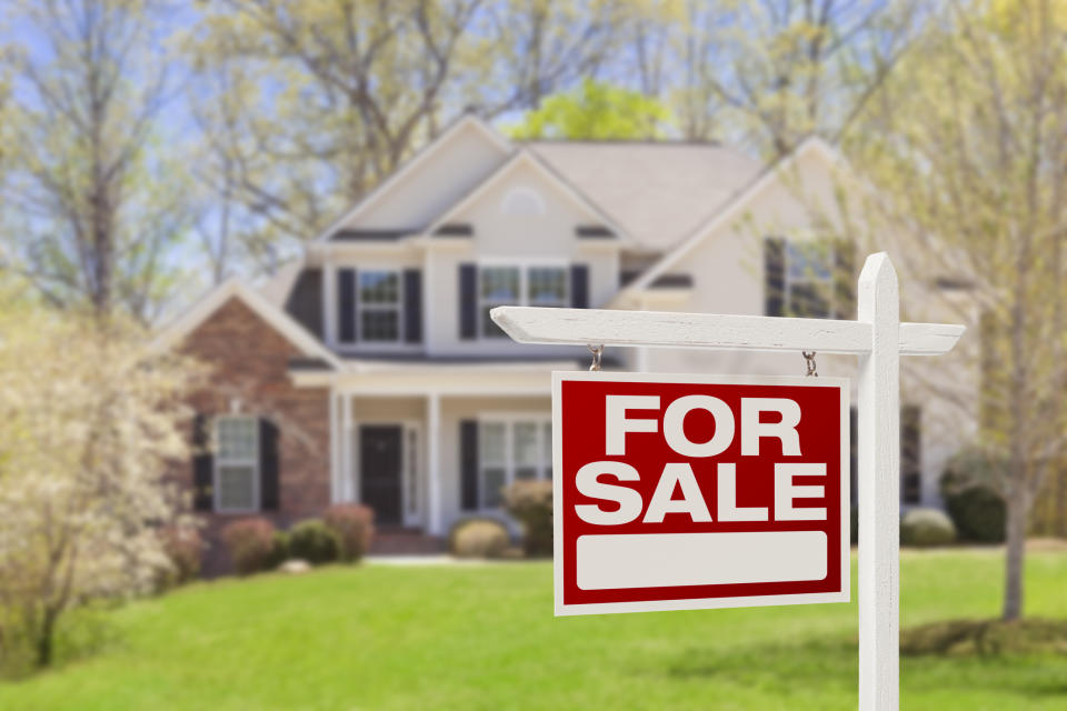 "For Sale" sign in front of a suburban house