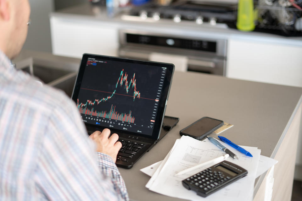 Anonymous man checks the stock market ion his tablet in TradingView in his kitchen