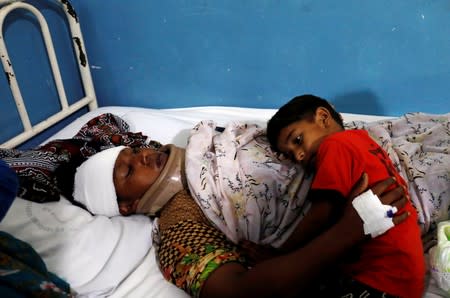 Eleven year-old Izik leans on his injured mother Nirmla, who lost her daughter, one and a half year-old Jesica, during an earthquake, at Divisional Headquarters Teaching Hospital Mirpur