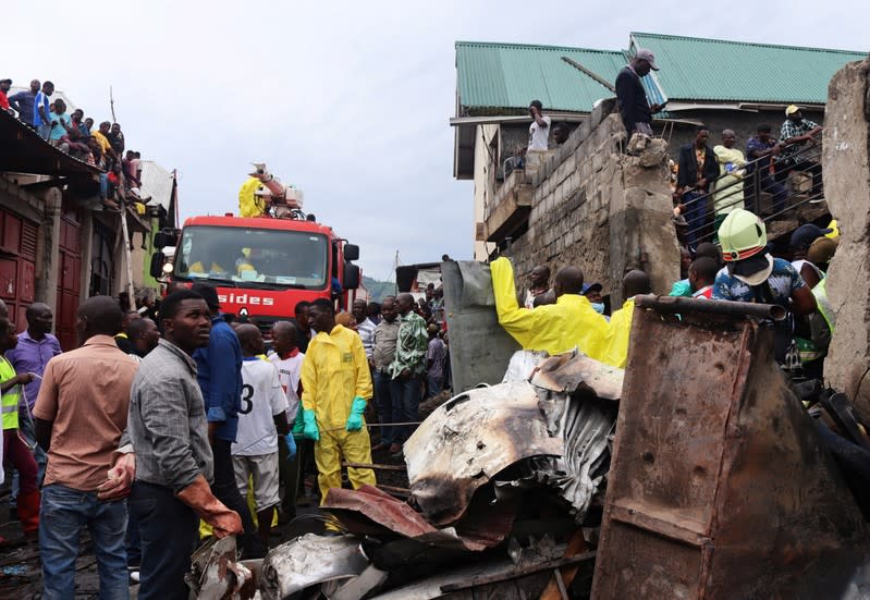 Rescuers and civilians gather at the site where a Dornier 228-200 plane operated by local company Busy Bee crashed into a densely populated neighborhood in Goma