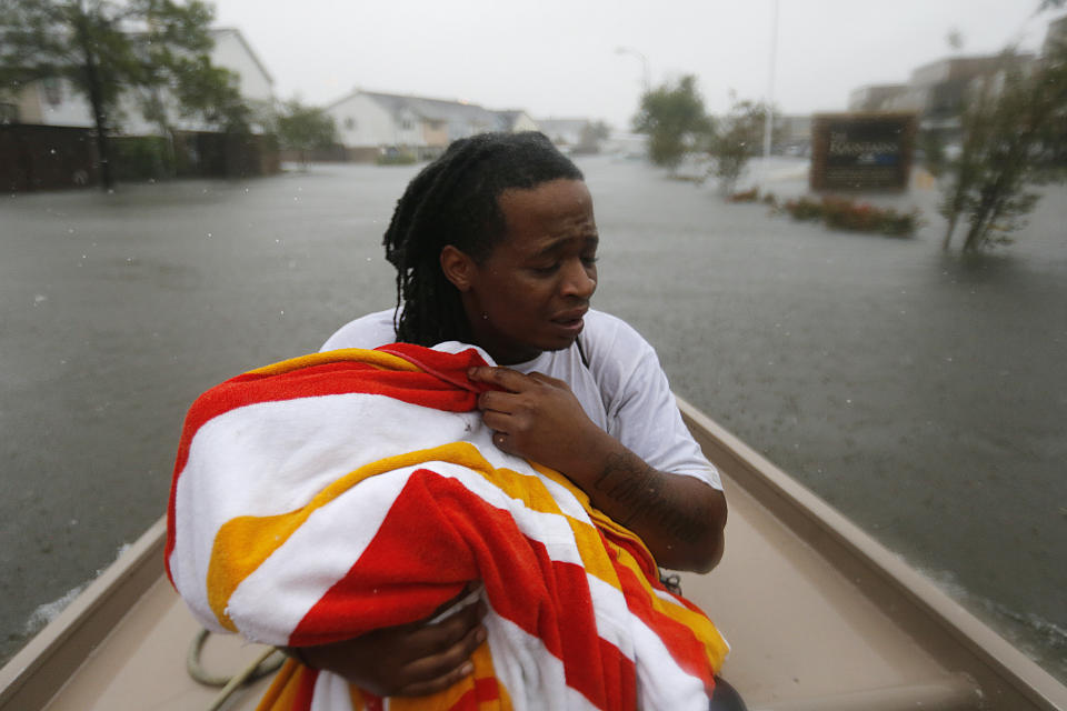 Demetres Fair holds a towel over his daughter Damouri Fair, 2, as they are rescued by boat by members of the Louisiana Department of Wildlife and Fisheries and the Houston Fire Department during flooding from Tropical Storm Harvey in Houston, Monday, Aug. 28, 2017. (AP Photo/Gerald Herbert)