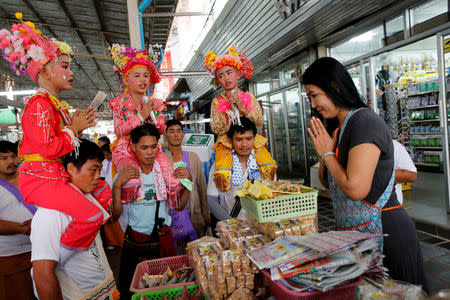 Phuwadol Kong Tawan (L), 11, Gorsak Kong Tawan (C), 13, and Danusorn Sdisaithaworn, 10, pray for a merchant at a market while being carried on shoulders during an annual Poy Sang Long celebration, a traditional rite of passage for boys to be initiated as Buddhist novices, in Mae Hong Son, Thailand, April 4, 2018. REUTERS/Jorge Silva