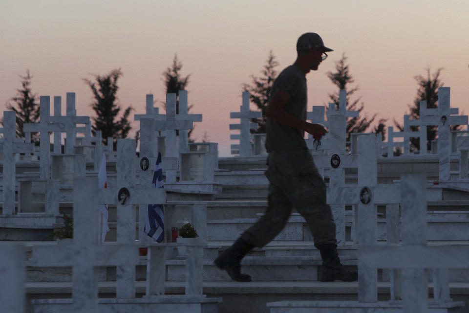 A soldier walks by the graves of soldiers killed in the 1974 Turkish invasion of Cyprus, in the Tymvos Macedonitissas military cemetery during the 45th anniversary in the divided capital of Nicosia, Cyprus, Friday, July 19, 2019. Some thousands of Greek and Cypriot soldiers were killed in 1974 during the Turkish invasion and subsequent occupation of the northern part of the island of Cyprus. (AP Photo/Petros Karadjias)