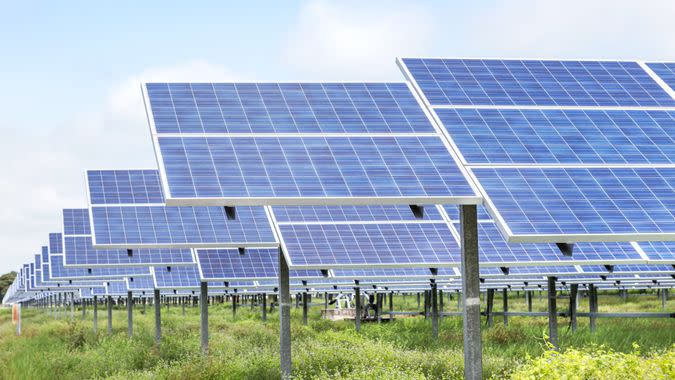 rows array of polycrystalline silicon solar cells or photovoltaics in solar power plant turn up skyward absorb the sunlight from the sun on blue sky background.