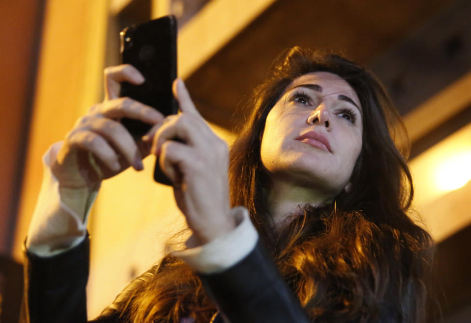 In this Wednesday, Dec. 4, 2019 photo, Lebanese anchorwoman Dima Sadek uses her cellphone to film an anti-government protest, in Beirut, Lebanon. Sadek, who last month resigned as an anchorwoman at the LBC TV, blamed Hezbollah supporters for robbing her smartphone while she was filming protests, and said the harassment was followed by insulting and threatening phone calls to her mother, who suffered a stroke as a result of the stress. (AP Photo/Hussein Malla)