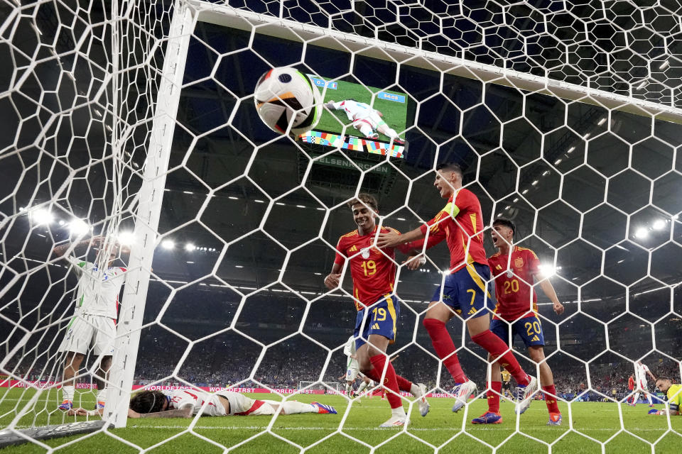 Spain's Lamine Yamal, center left, celebrates as Italy's Riccardo Calafiori lies on the pitch after he scored an own goal during a Group B match between Spain and Italy at the Euro 2024 soccer tournament in Gelsenkirchen, Germany, Thursday, June 20, 2024. (AP Photo/Martin Meissner)