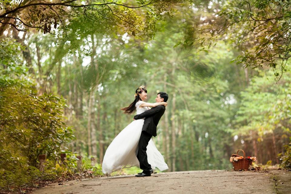 A married couple standing on a road in a forest area