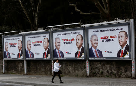 A woman walks past by AK Party billboards with pictures of Turkish President Tayyip Erdogan and mayoral candidate Binali Yildirim in Istanbul, Turkey, April 1, 2019. The billboards read: " Thank you Istanbul ". REUTERS/Murad Sezer