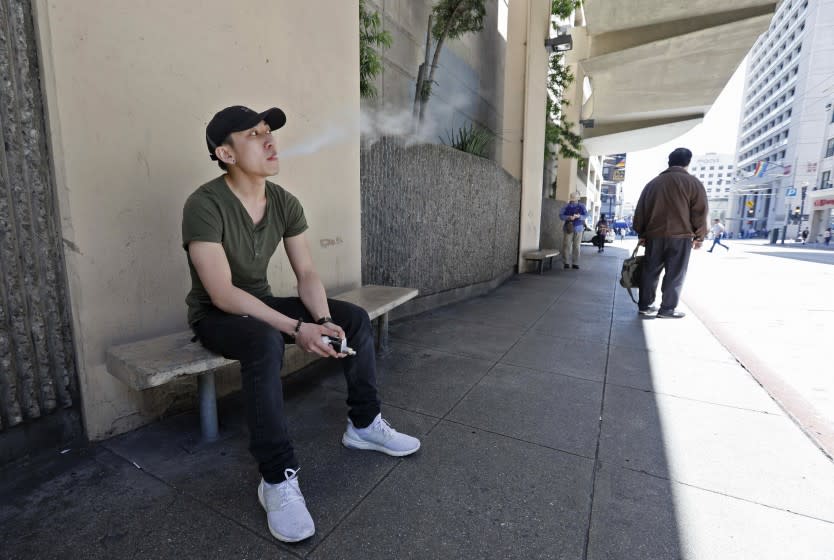 FILE - In this June 17, 2019, file photo, Jacky Chan takes a vaping break from his job at a smoke shop in San Francisco. City officials in San Francisco have voted to ban all tobacco smoking inside apartments, citing concerns about secondhand smoke. The Board of Supervisors voted 10-1 Tuesday, Dec. 1, 2020, to approve the ordinance making San Francisco the largest city in the country to ban tobacco smoking inside apartments, the San Francisco Chronicle reported. Supervisors voted to exclude marijuana after cannabis activists said the law would take away their only legal place to smoke. (AP Photo/Samantha Maldonado, File)