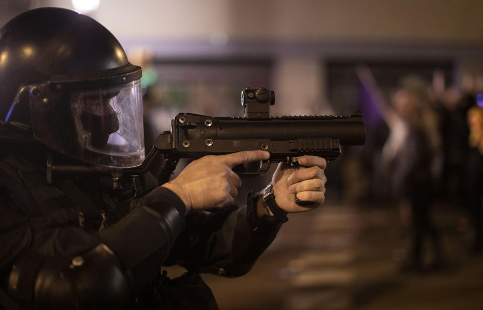 A Catalan police officer aims his weapon against demonstrators during clashes in Barcelona, Spain, Saturday, Oct. 26, 2019. Protests turned violent last week after Spain's Supreme Court convicted 12 separatist leaders of illegally promoting the wealthy Catalonia region's independence and sentenced nine of them to prison. (AP Photo/Emilio Morenatti)