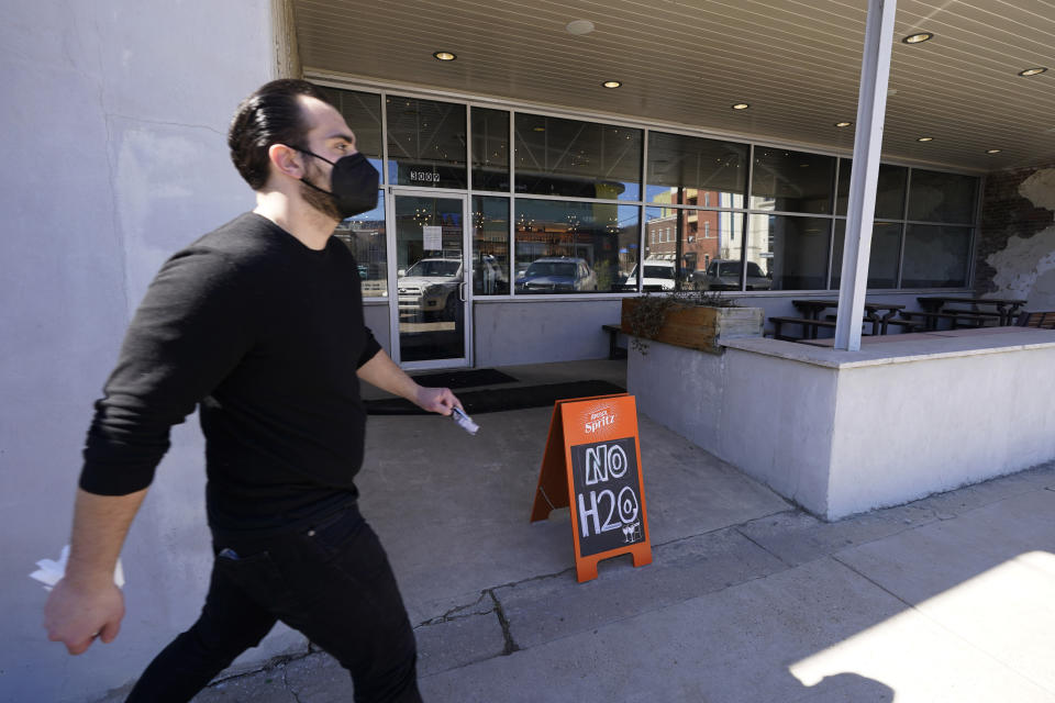 FILE - In this Feb. 23, 2021, file photo, resident walks past a sign outside Barrelhouse restaurant that states it has no running water in Jackson, Miss. The snow and ice that crippled some states across the South has melted. But it has exposed the fragility of aging waterworks that experts have been warning about for years. Cities across Texas, Tennessee, Louisiana and Mississippi are still grappling with outages that crippled health care facilities and forced families to wait in line for potable water. (AP Photo/Rogelio V. Solis, File)