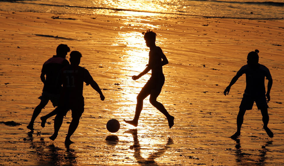 Indian youngsters play football on beach