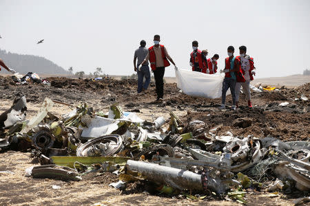 Ethiopian Red Cross workers carry a body bag with the remains of Ethiopian Airlines Flight ET 302 plane crash victims at the scene of a plane crash, near the town of Bishoftu, southeast of Addis Ababa, Ethiopia March 12, 2019. REUTERS/Baz Ratner