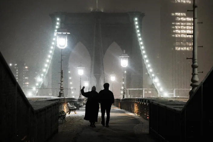 Snow falls as people walk across the Brooklyn Bridge in New York City on Monday night. (Spencer Platt / Getty Images)