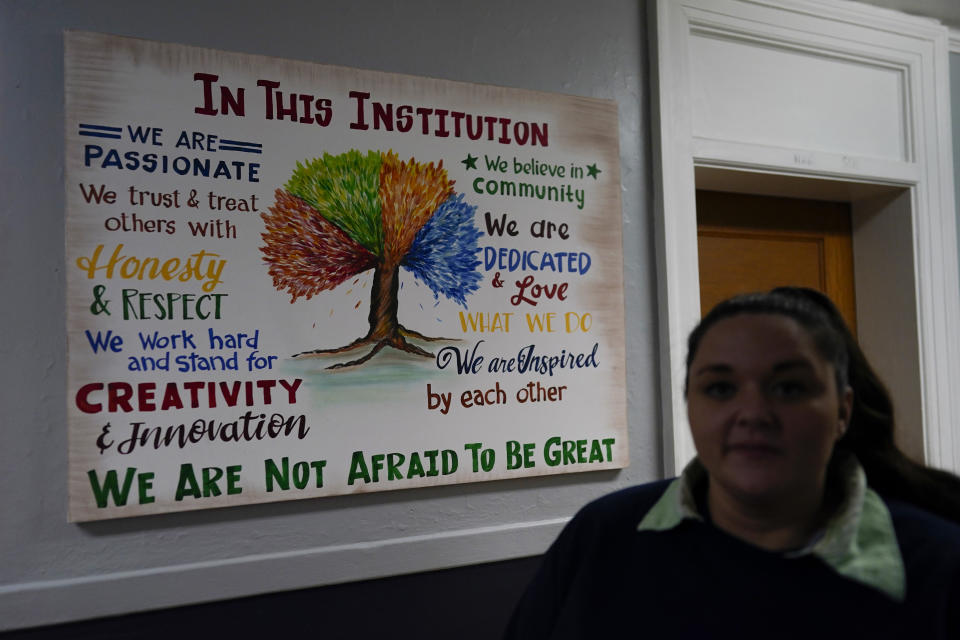 Heather Jarvis walks past a sign hanging in a hallway at the Ohio Reformatory for Women in Marysville, Ohio, Thursday, Oct. 19, 2023. Jarvis is part of the fastest-growing prison population in the country, one of more than 190,000 women held in some form of confinement in the United States as of this year. Their numbers grew by more than 500% between 1980 and 2021. (AP Photo/Carolyn Kaster)