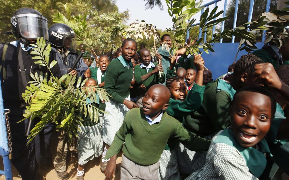 Students from Langata primary school run past riot police as they protest against a perimeter wall illegally erected by a private developer around their school playground in Nairobi