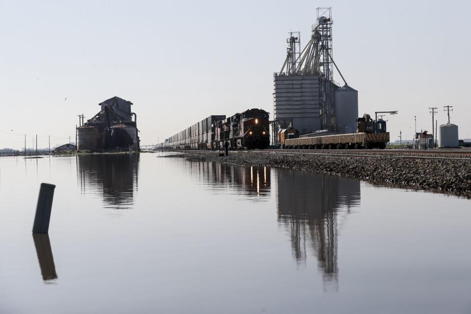 A freight train passes by flooded fields.