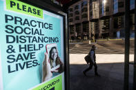 A man passes a COVID-19 public service notice in San Francisco's financial district on Wednesday, Oct. 21, 2020. As the coronavirus pandemic transforms San Francisco's workplace, legions of tech workers have left, able to work remotely from anywhere. Families have fled for roomy suburban homes with backyards. The exodus has pushed rents in the prohibitively expensive city to their lowest in years. (AP Photo/Noah Berger)