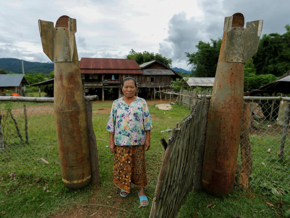 A woman poses at an entrance of her house next to bombs dropped by the U.S. Air Force planes during the Vietnam War, in the village of Ban Napia in Xieng Khouang province, Laos