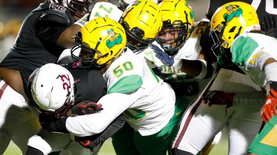 Bryan Station’s Jahvon Frazier (50) and a host of Defender teammates bring down Tates Creek’s Tony Bell (22).