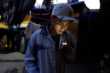 Honduran migrant Ariel, 19, who is waiting for his court hearing for asylum seekers, that have been returned to Mexico to await their legal proceedings under a new policy established by the U.S. government, checks his cellphone at a shelter in Tijuana, Mexico, March 19, 2019. REUTERS/Jorge Duenes