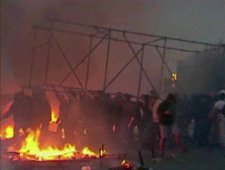 This image made from AP video shows people carrying a scaffolding frame through fires on the ground in Odessa, Ukraine, on Friday, May 2, 2014. Deadly clashes took place in the southern Ukraine port of Odessa on Friday, triggered by Ukraine's offensive to recapture the eastern city of Slovyansk from pro-Russia forces. (AP Photo via AP Video)