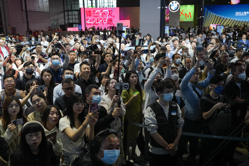 Attendees film the BMW's new electric flagship models after being unveiled in the press day of the Auto Shanghai 2023 at the National Exhibition and Convention Center in Shanghai, China, Tuesday, April 18, 2023. Global and Chinese automakers plan to unveil more than a dozen new electric SUVs, sedans and muscle cars this week at the Shanghai auto show, their first full-scale sales event in four years in a market that has become a workshop for developing electrics, self-driving cars and other technology. (AP Photo/Ng Han Guan)