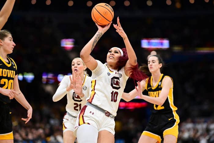 Female basketball player #10 leaps for a layup during a game, surrounded by opponents