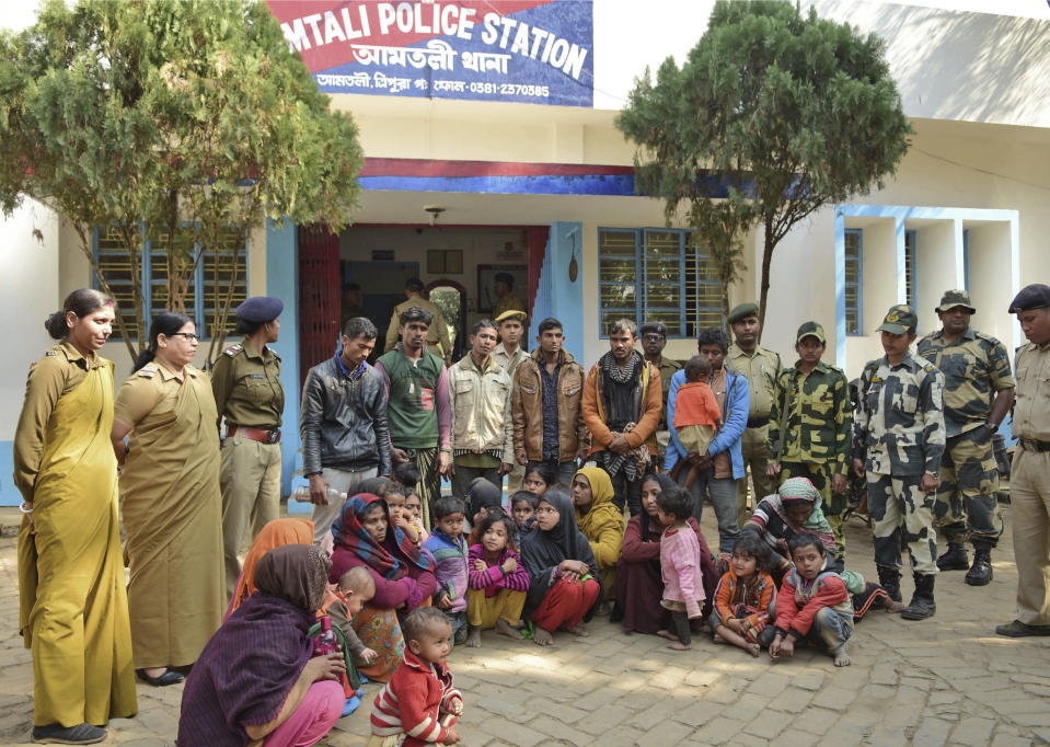 Indian police officials stand next to Rohingya Muslims after they were arrested in two northeastern states, outside a police station in Agartala, India, Tuesday, Jan. 22, 2019. Police in northeastern India say they have arrested 61 Rohingya Muslims this week amid reports that more than 1,300 have recently crossed the border into Bangladesh. (AP Photo/Abhisek Saha)