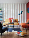 <p> Although this coffee table is small, it’s still key to this living room. It ties in because it has black legs like the sofa, chair, and side table on the right. And the yellow vase completely matches the yellow sofa, and the orange bowl matches the orange chair for perfect color symmetry. </p>