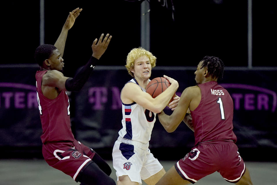 Liberty's Drake Dobbs, center, is pressured by South Carolina's Keyshawn Bryant, left, and T.J. Moss (1) during the second half of an NCAA college basketball game Saturday, Nov. 28, 2020, in Kansas City, Mo. (AP Photo/Charlie Riedel)