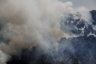 A Lebanese army helicopter drops water over a forest fire, at Qobayat village, in the northern Akkar province, Lebanon, Thursday, July 29, 2021. Lebanese firefighters are struggling for the second day to contain wildfires in the country's north that have spread across the border into Syria, civil defense officials in both countries said Thursday. (AP Photo/Hussein Malla)