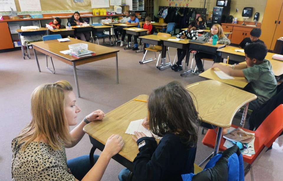 Pfeiffer-Burleigh Elementary School teacher Bethany Kaiser, left, talks with fifth-grade student Jett Curtiss, 10, about a poetry assignment. New statewide data shows that Erie students not only exceeded the standards in math, English/language and science categories last school year, they were well above the benchmarks.