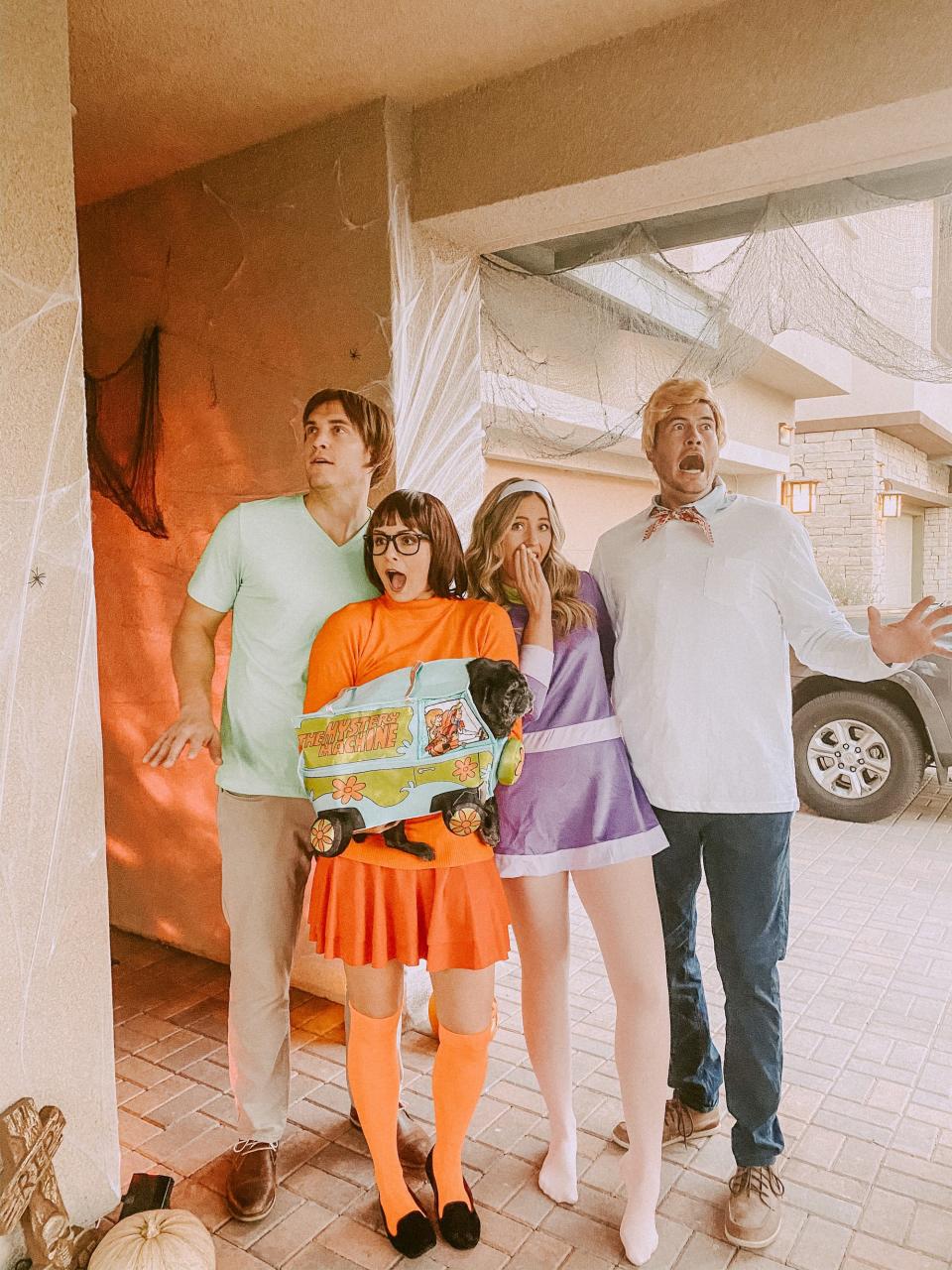 A group of four dressed as Shaggy, Velma, Daphne, and Fred from "Scooby Doo" pose for a photo.