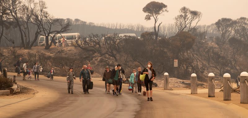 An image obtained on January 3, 2020, shows bushfire evacuees walking down to the beach to board vessels and be ferried out to HMAS Choules at Mallacoota