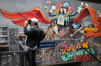 BRISTOL, ENGLAND - AUGUST 17: A man photographs part of the 'See No Evil' street art project at Nelson Street on August 17, 2012 in Bristol, England. The project, now in its second year, is Europe's biggest street art festival and has attracted top graffiti artists from all over the world. Organizers hope it will continue to be a draw for tourists visiting Bristol, often seen the spiritual home of underground artist Banksy. (Photo by Matt Cardy/Getty Images)