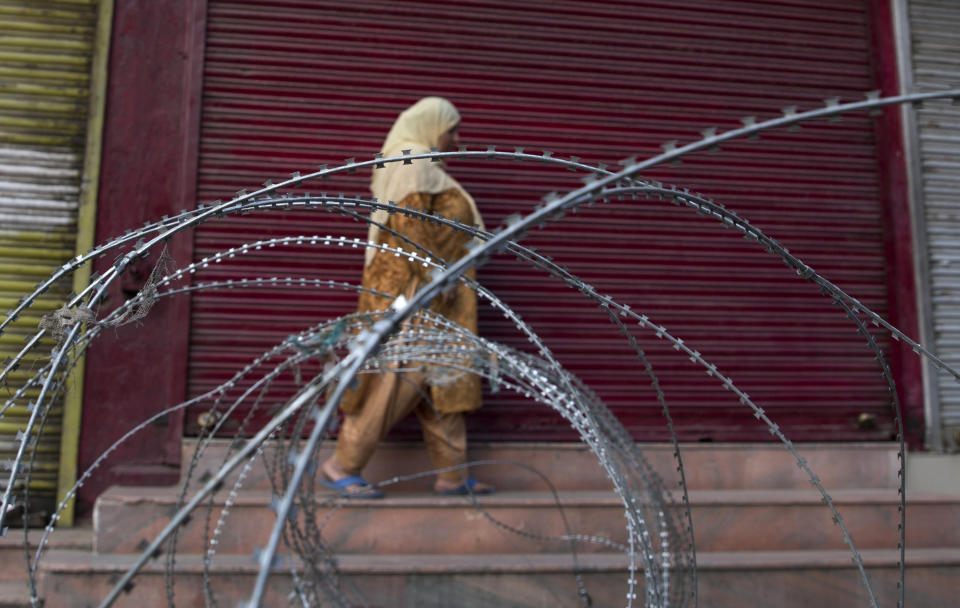 A Kashmiri woman walks past a barbed wire barricade set up by paramilitary soldiers during restrictions in Srinagar Indian controlled Kashmir, Friday, Sept. 27, 2019. Residents in Indian-controlled Kashmir waited anxiously as Indian and Pakistani leaders were scheduled to speak at the U.N. General Assembly later Friday. (AP Photo/ Dar Yasin)