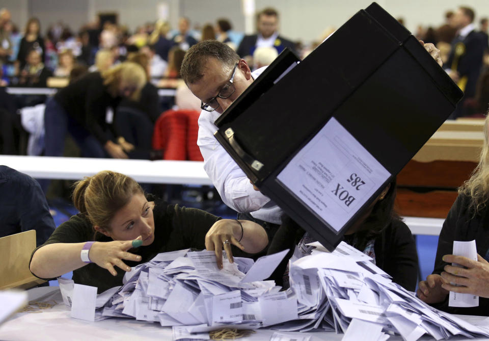 A ballot counter crouches down as a full box of ballots is poured onto her desk.