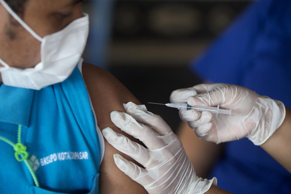 A health worker administers Moderna COVID-19 booster shot to man during a third dose vaccination campaign in Denpasar, Bali, Indonesia on Saturday, Jan. 29, 2022. Indonesia is bracing for a third wave of COVID-19 infections as the highly transmissible omicron variant drives a surge in new cases, health authorities and experts said Saturday. (AP Photo/Firdia Lisnawati)