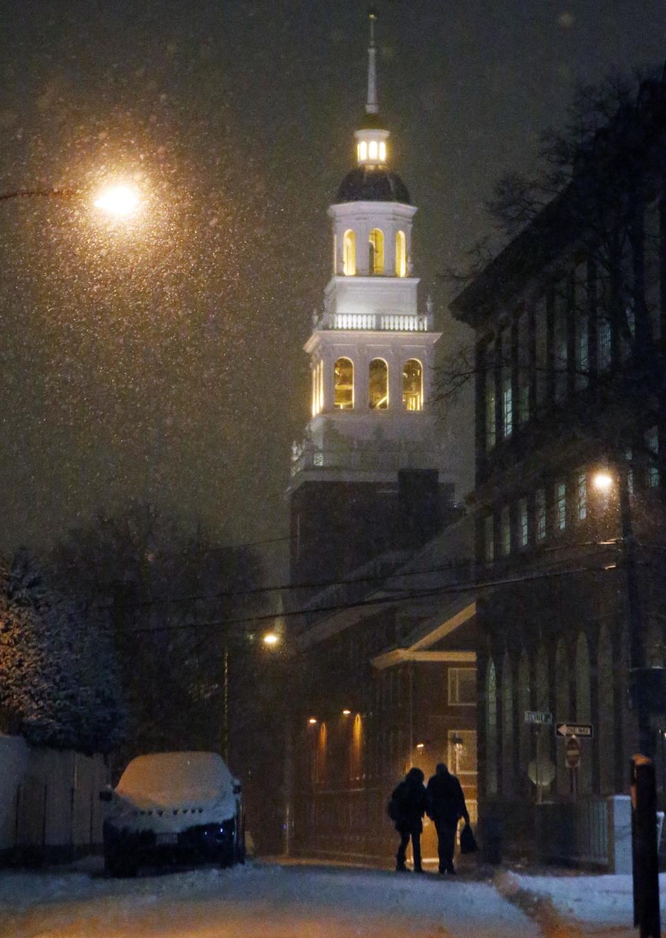 A couple walk as snow falls in Harvard Square in Cambridge, Mass. Tuesday, Jan. 21, 2014. Heavy snow has been forecast and a blizzard warning was posted for portions of Massachusetts. (AP Photo/Elise Amendola)