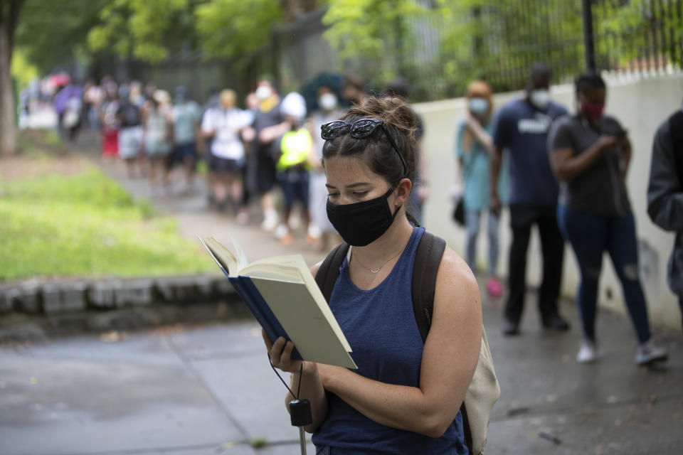 Kelsey Luker reads as she waits in line to vote on June 9 in Atlanta. Luker said she had been in line for almost two hours. Voters reported wait times of three hours. (Photo: ASSOCIATED PRESS/John Bazemore)