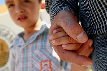 Salvadoran migrant Epigmenio Centeno holds the hand of his three-year old son Steven Atonay outside the shelter House of the Migrant, after he has decided to stay with his children in Mexico due to U.S. President Donald Trump's child separation policy, in Ciudad Juarez, Mexico June 19, 2018. REUTERS/Jose Luis Gonzalez