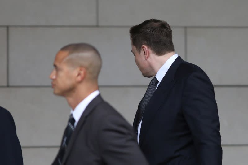 Elon Musk walks with his face turned away from cameras as he arrives at court for trial in Los Angeles