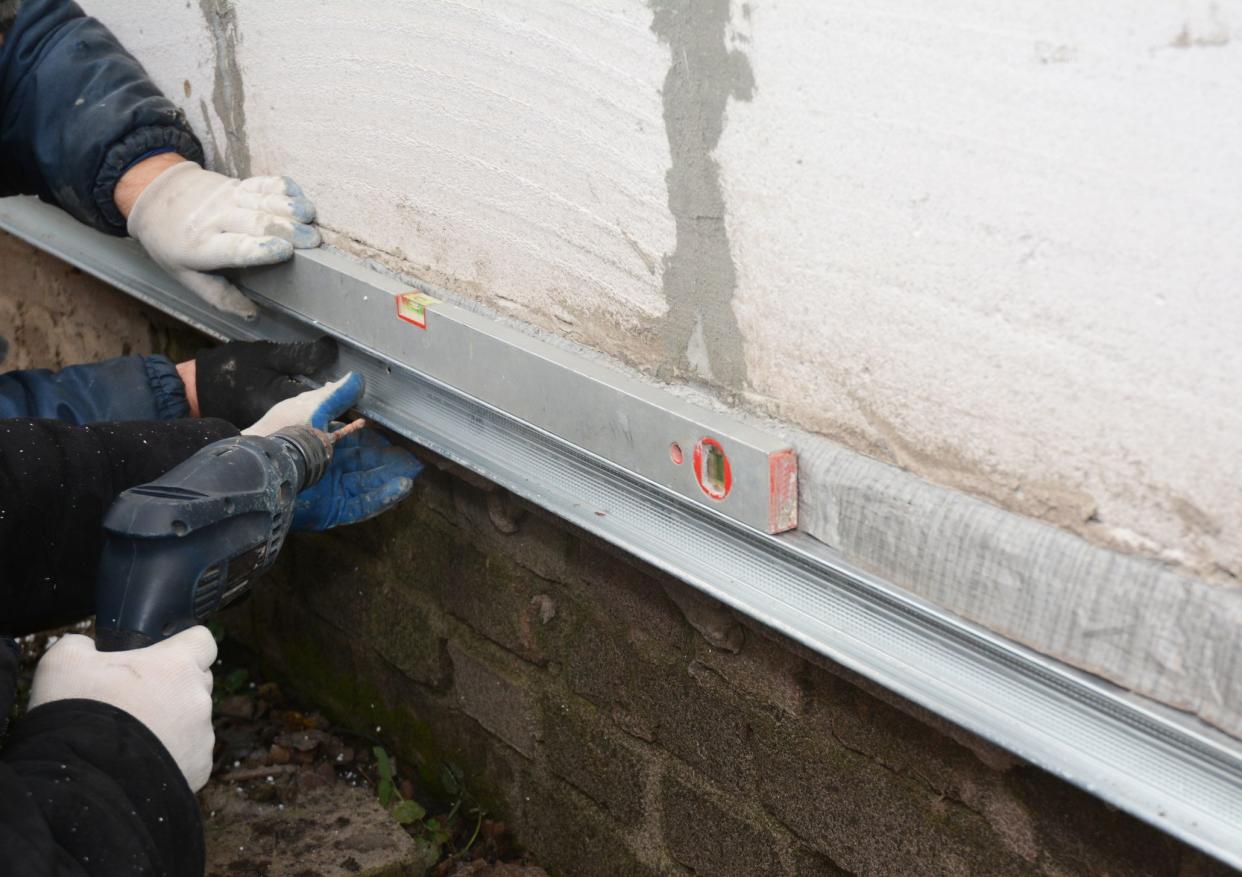 Old house foundation wall repair and renovation  with installing metal sheets for waterproofing and protect from rain. Contractors with Foundation repair.