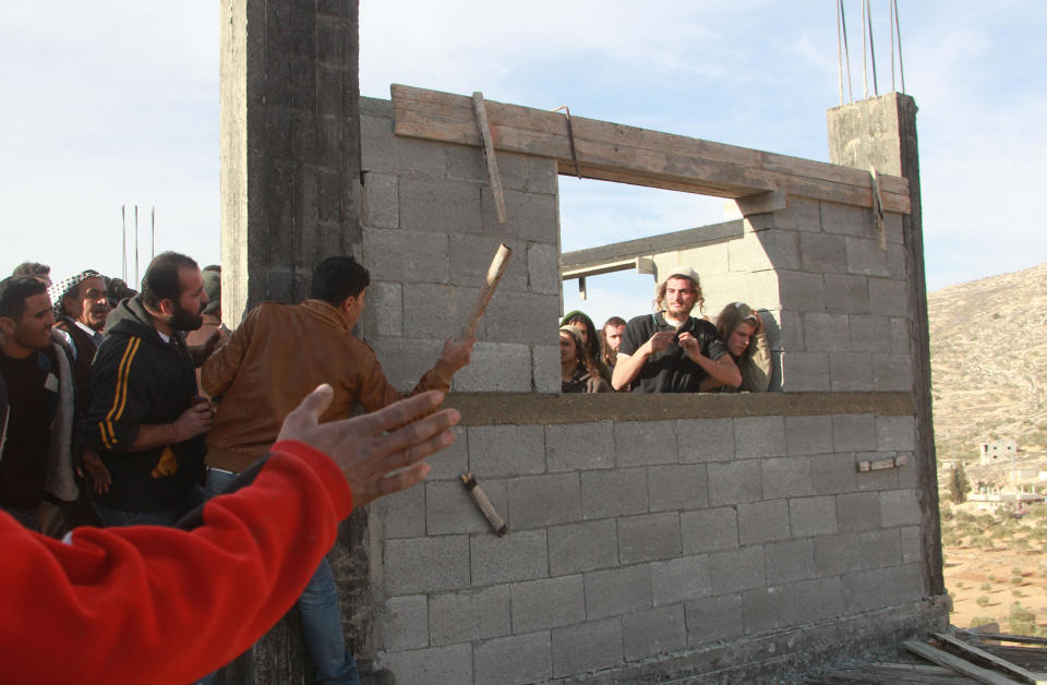 A Palestinian man from the village of Qusra threatens with a stick a group of Israeli settlers as they cornered them at a construction site after they sparked clashes upon entering the Palestinian village near Nablus, in the Israeli occupied West Bank, on January 7, 2014. (JAAFAR ASHTIYEH/AFP/Getty Images)