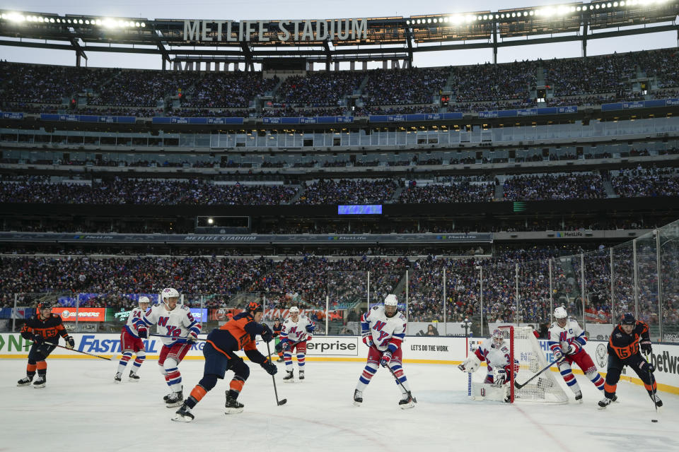 New York Islanders Cal Clutterbuck, right, brings the puck around the goal during the second period of an NHL Stadium Series hockey game against the New York Rangers in East Rutherford, N.J., Sunday, Feb. 18, 2024. (AP Photo/Seth Wenig)